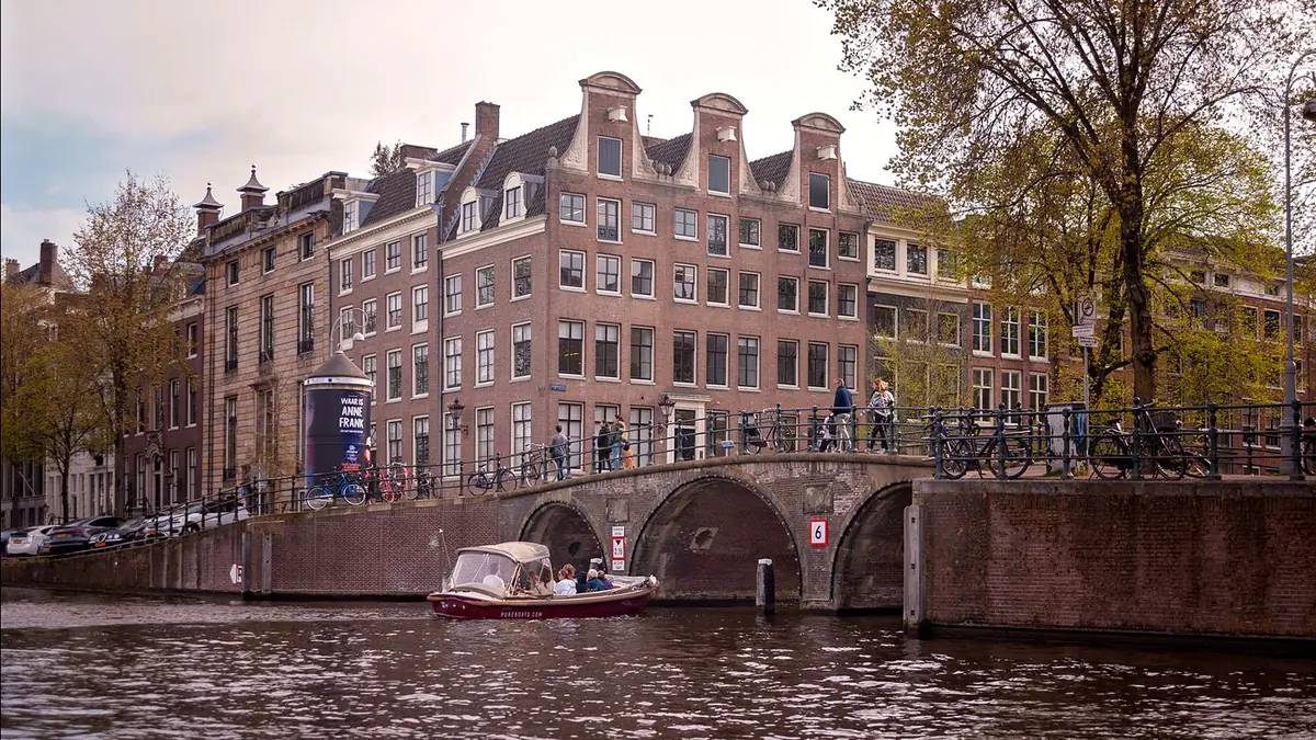 Amsterdam entdecken: Grachtenboot unter einer Backsteinbrücke